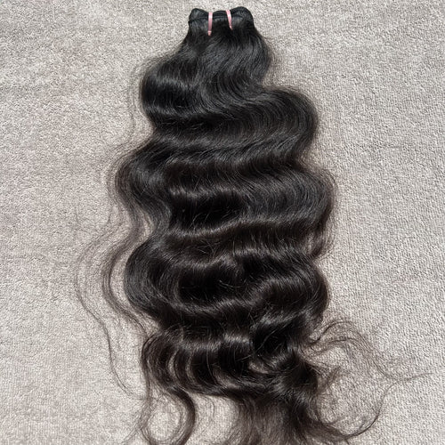 Black wavy hair bundle on a gray textured background