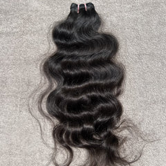 Black wavy hair bundle on a gray textured background