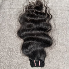 Black hair bundle with loose curls on a textured gray background