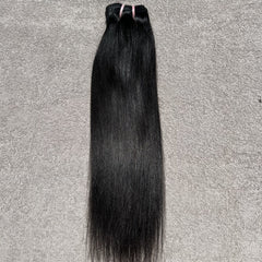 Bundle of straight black hair on a gray background