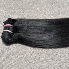 Bundle of black hair extensions on a gray surface