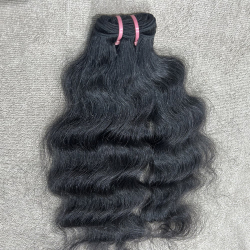 Bundle of wavy black hair on a textured gray surface
