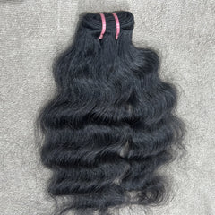 Bundle of wavy black hair on a textured gray surface