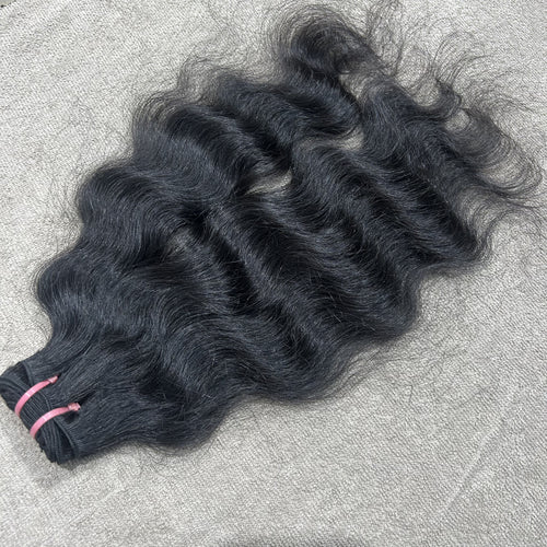 Three bundles of wavy black hair on a textured gray surface