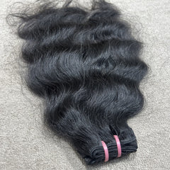 Bundle of black hair extensions on a textured gray surface