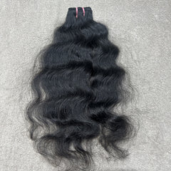 Black wavy hair bundle on a gray textured background
