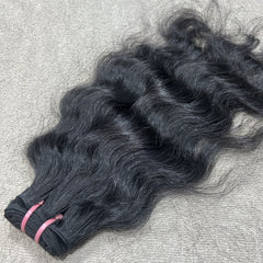 Bundles of black hair extensions on a textured surface