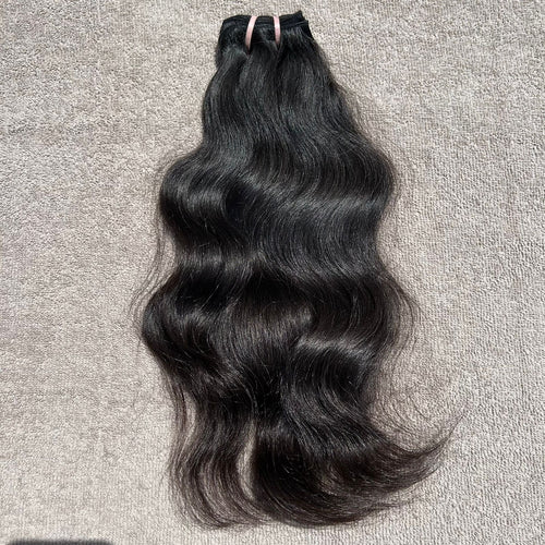 Black hair bundle with wavy texture on a gray surface